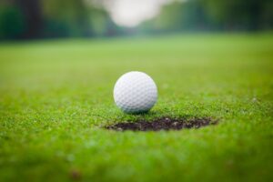 golf ball on lip of cup. Golf ball on green grass in golf course