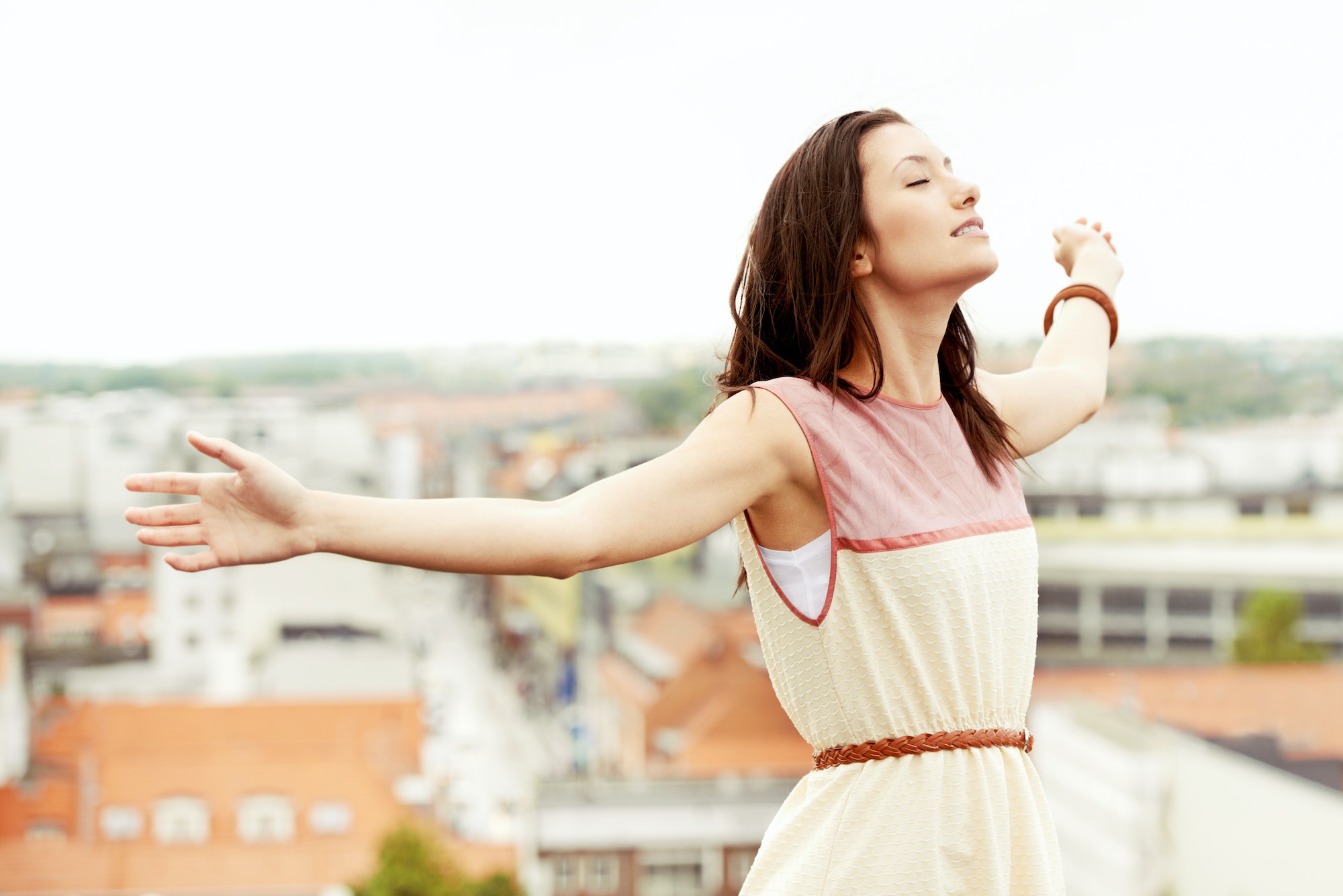 Letting go and feeling free. Gorgeous young woman standing on a rooftop with her arms outstretched.